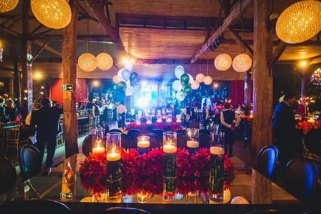 Show ao vivo em salão de festa decorado com velas e flores vermelhas