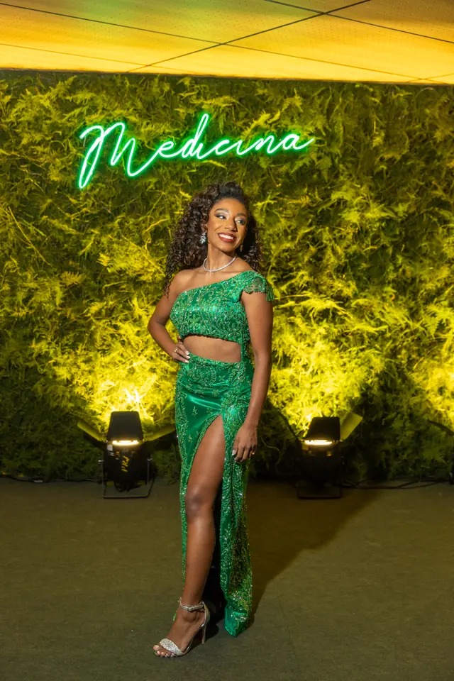 Formanda de Medicina posando diante de neon com a palavra Medicina